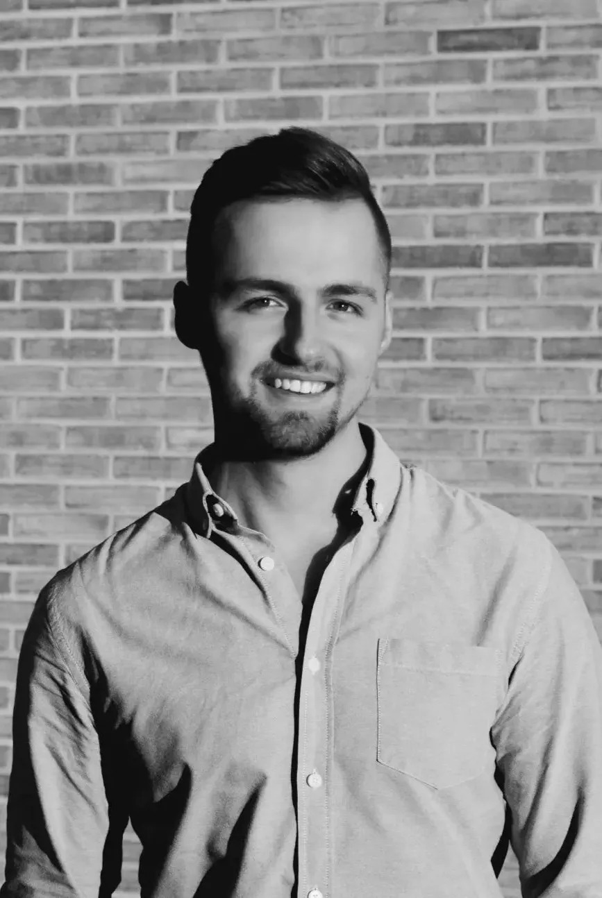 Porträtfoto von Christian Rauscher vor einer Backsteinwand in schwarz/weiß.