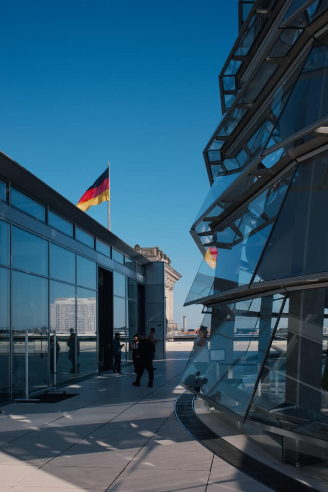 Eine wehende Deutschlandflagge auf dem Dach des Reichstagsgebäudes neben der Glaskuppel.