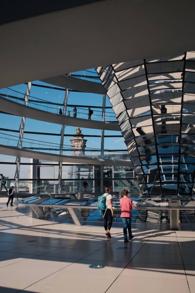 Zwei Besucher gehen auf der Rampe innerhalb der gläsernen Kuppel des Reichstagsgebäudes.