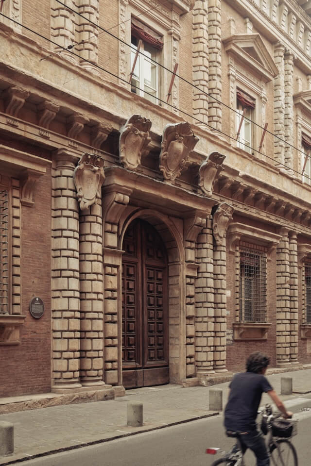 Ein Radfahrer fährt an der verzierten Steinfassade eines alten Palastes vorbei.