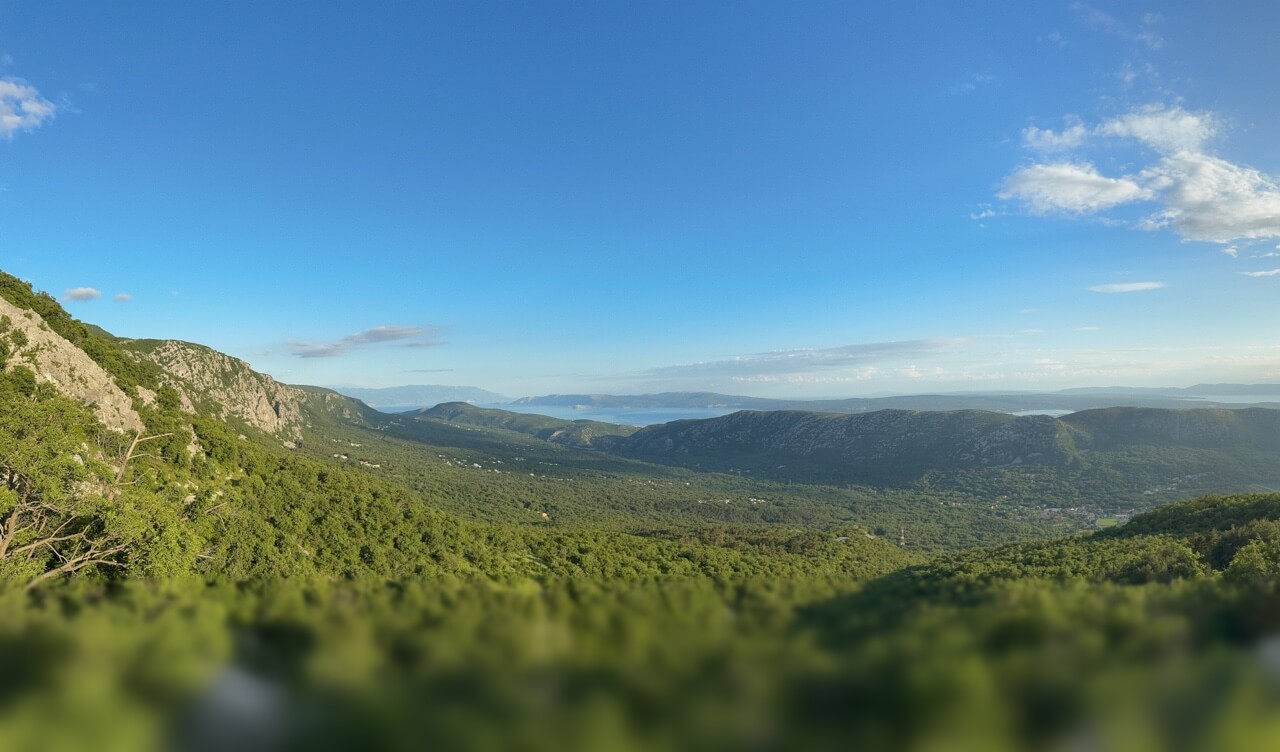 Eine weite, hügelige Landschaft mit grünen Wäldern auf der Insel Krk mit Blick auf das Meer.