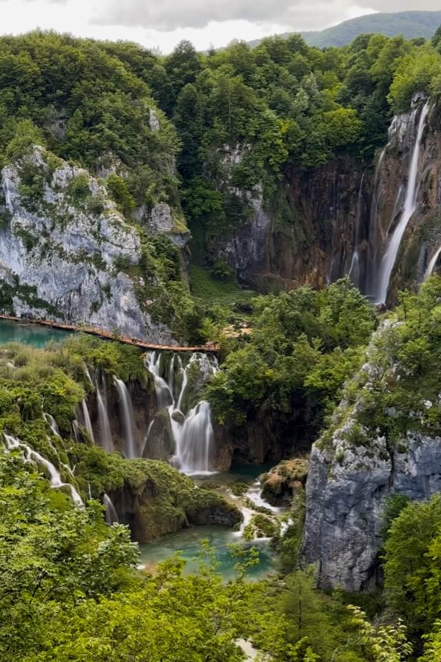 Viele Wasserfälle stürzen in einer bewaldeten Schlucht der Plitvicer Seen in die Tiefe.