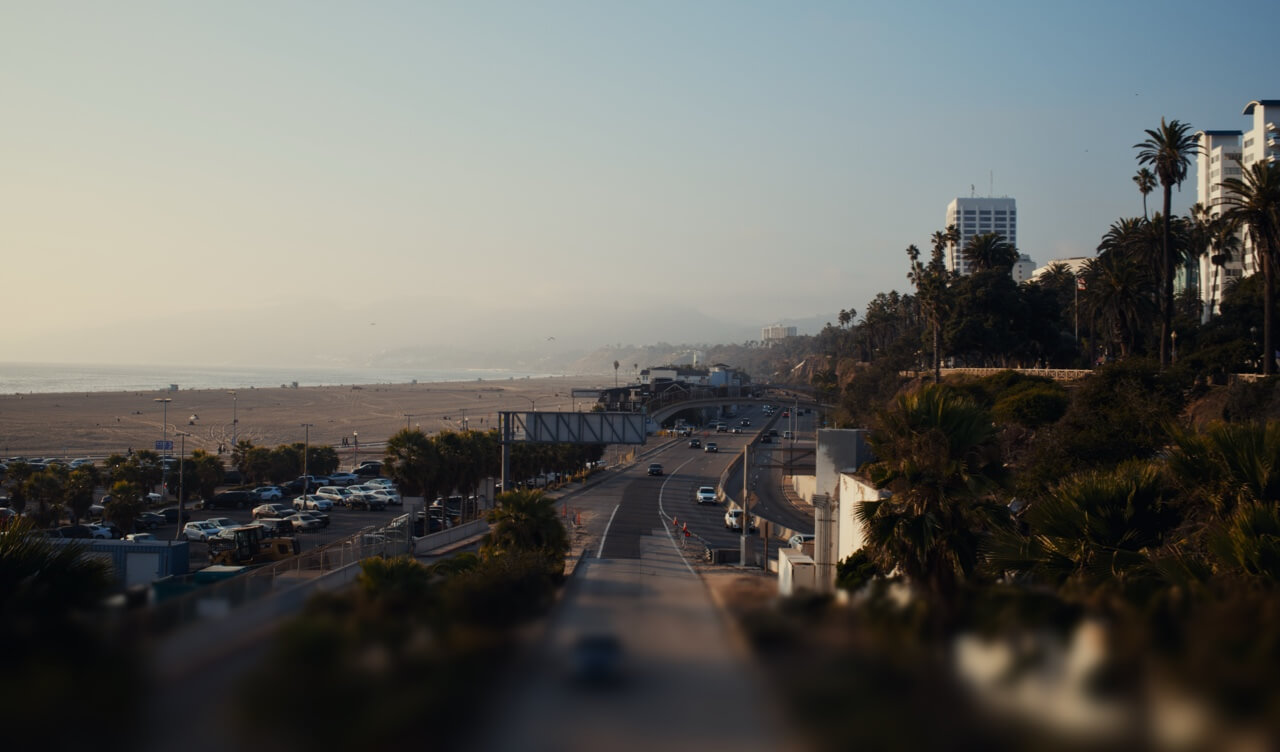 Blick auf den Pacific Coast Highway, der bei Dunst am weiten Sandstrand von Santa Monica entlangführt.