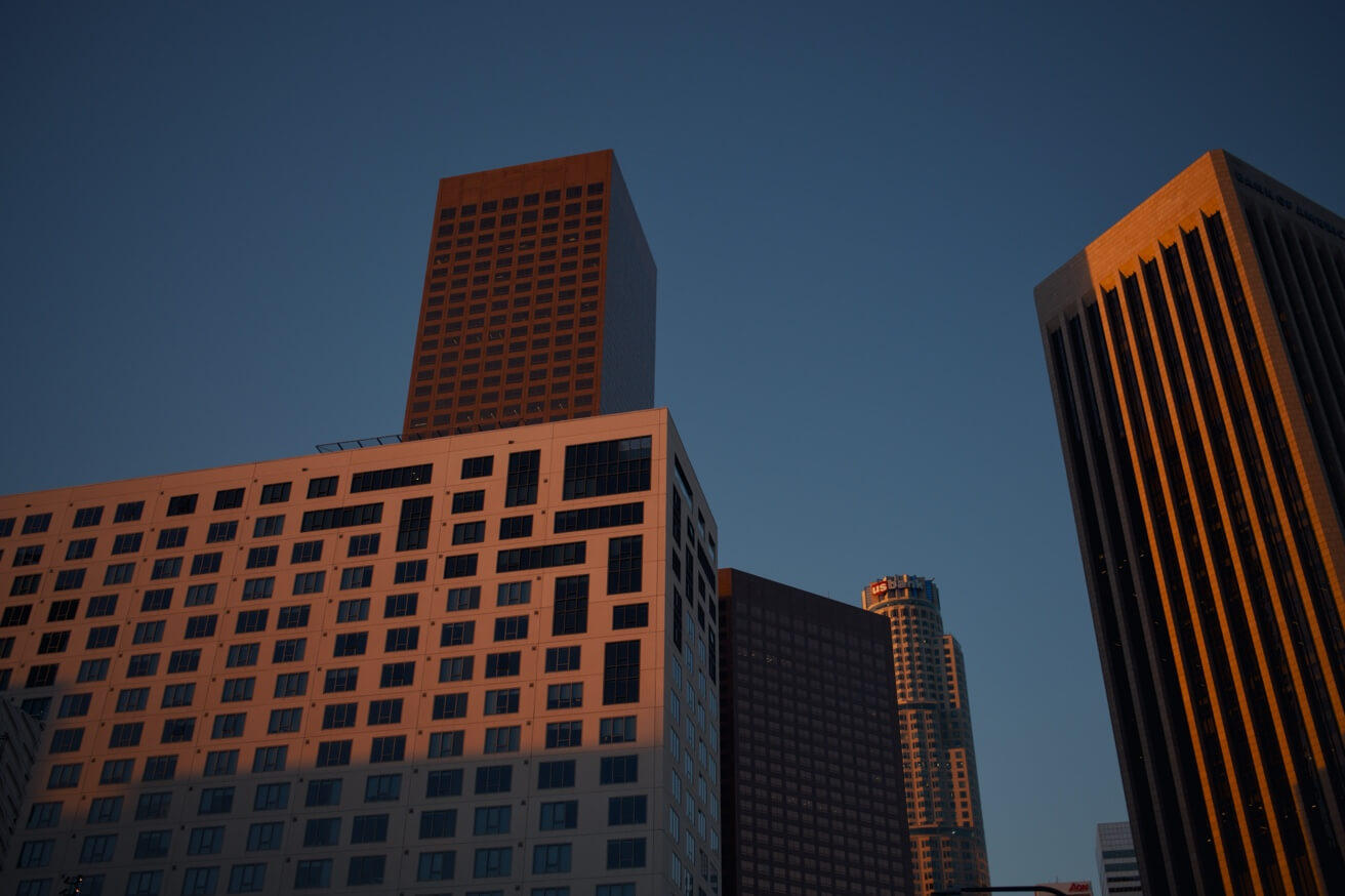 Wolkenkratzer in der Innenstadt von Los Angeles werden von der tiefstehenden Sonne in ein warmes, goldenes Licht getaucht.
