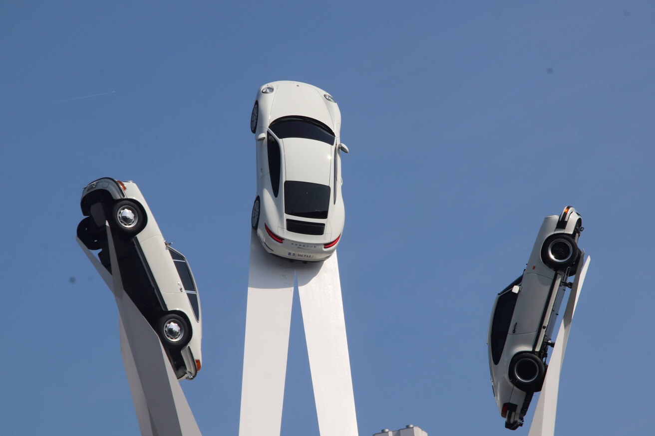 Die Skulptur vor dem Porsche Museum mit drei weißen Porsche 911 auf hohen Pfeilern.