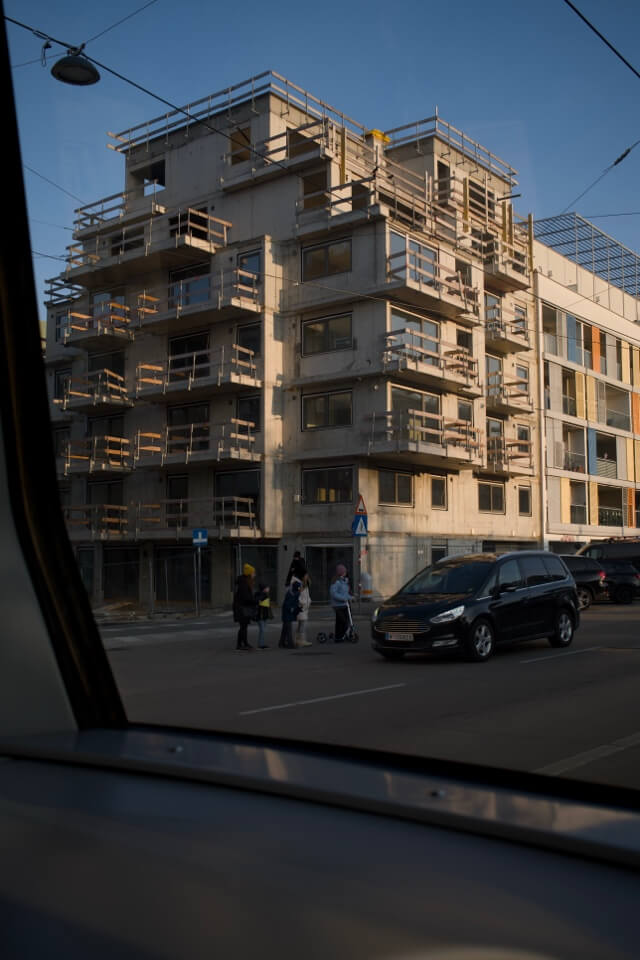 Ein mehrstöckiges Wohnhaus im Rohbau mit unfertigen Balkonen an einer Straßenecke.