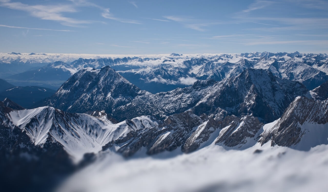 Ein weites Panorama von unzähligen schneebedeckten Berggipfeln der Alpen unter blauem Himmel.