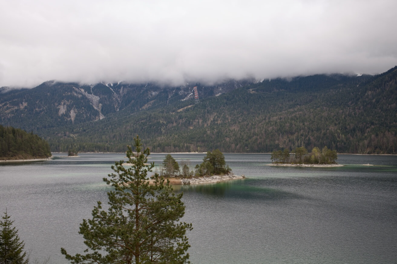 Der Eibsee mit seinen kleinen, baumbewachsenen Inseln an einem bewölkten Tag vor einer Bergkulisse.