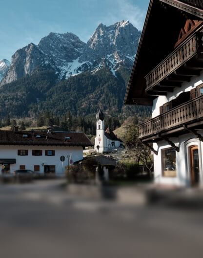 Das bayerische Alpendorf Grainau mit seiner Kirche vor dem gewaltigen Zugspitzmassiv.