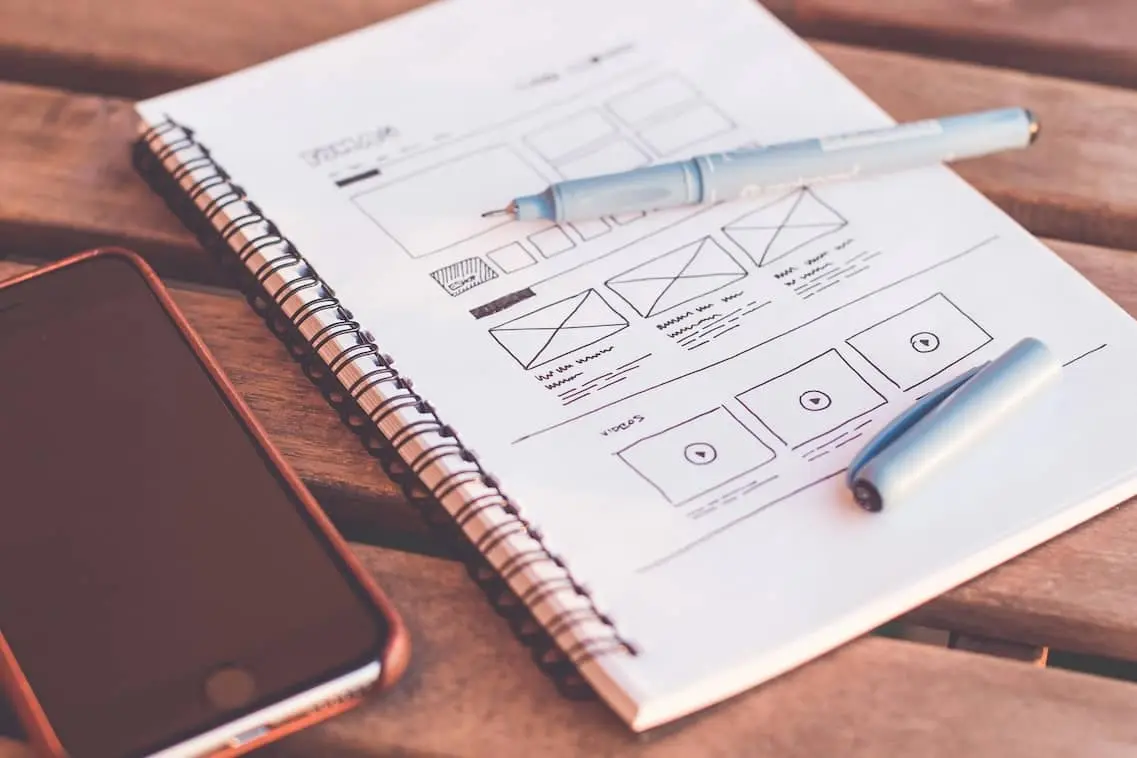 Webdesign Skizze auf Notizblock mit Stift und Smartphone