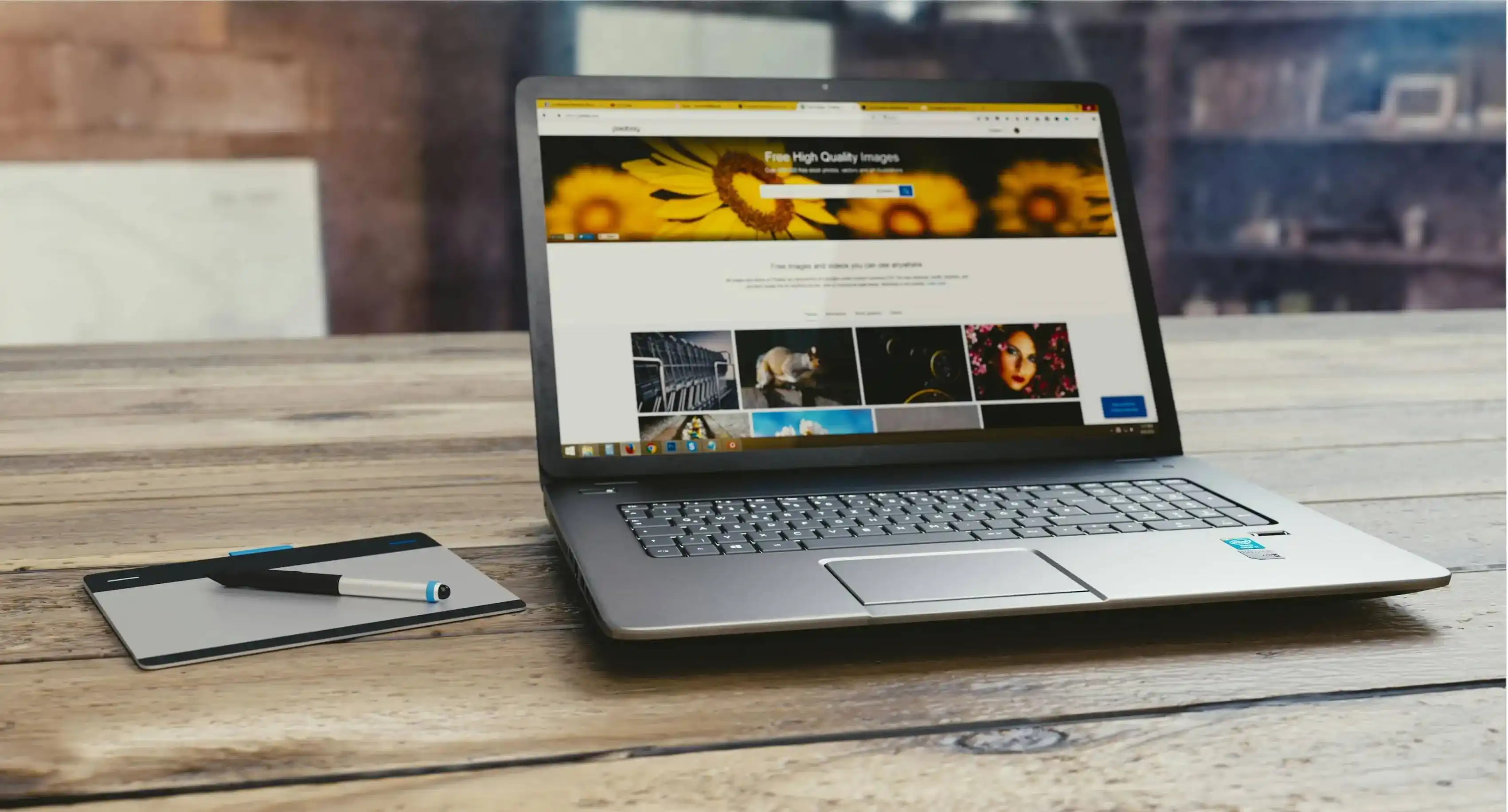 Auf einem Tisch liegt ein aufgeklappter Laptop. Auf dem Bildschirm sieht man eine Website für Fotografie. Neben dem Laptop liegt ein Notizblock mit Stift.